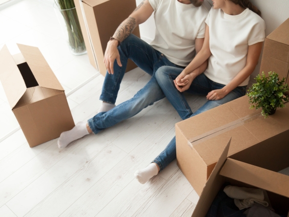 Close up of happy couple sitting on floor with boxes